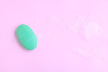 Green soap bar with soap foam on pink background, Soap and bubble, Top view