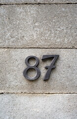 House number numerals on a concrete wall. Number 87 decorative types, close up, no people