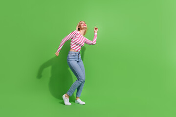 Full length photo of sweet positive girl dressed striped shirt dancing discotheque empty space isolated green color background