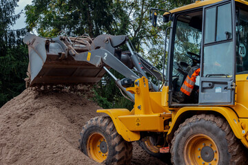 Radlader auf Baustelle fährt auf Sandberg