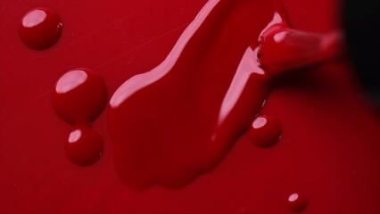 Red nail polish drops, manicure concept. Spilled uv gel, enamel, varnish with brush on red color background, splash. Beauty salon, nail care product. Nail art. Top view, fashion backdrop. Slow motion 