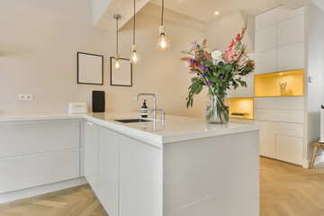 a modern kitchen with white cabinets and an island in the middle part of the room there is a vase of flowers