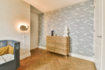 a baby's room with grey and white birds on the wallpaper, wooden cribe dresser and changing table