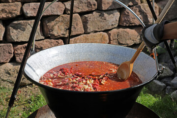 Meat and vegetables in a goulash kettle on a fire pit