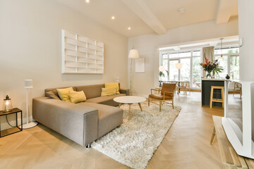 a living room with white walls and wood flooring in the center of the room, there is a grey couch