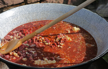 Meat and vegetables in a goulash kettle on a fire pit
