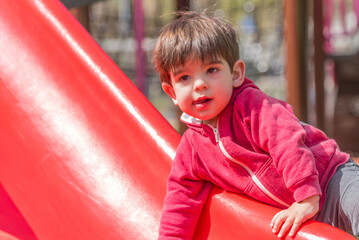 Fototapeta na wymiar Child having fun climbing the slide in the playground.