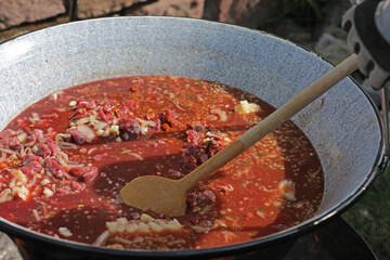 Meat and vegetables in a goulash kettle on a fire pit