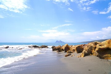 Fototapeta na wymiar View from a rocky stretch of coast at La Alcaidesa across the Mediterranean to the Rock of Gibraltar, Playa de Torrecarbonera, Andalusia, Costa del Sol, Malaga, Spain