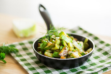 Sliced zucchini fried with onions and herbs in a frying pan