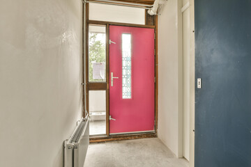 a pink door in a white room with blue walls and wood trim on the wall behind it is an open doorway