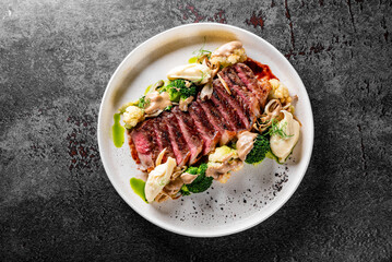Cooked sliced beef steak rare with green broccoli.