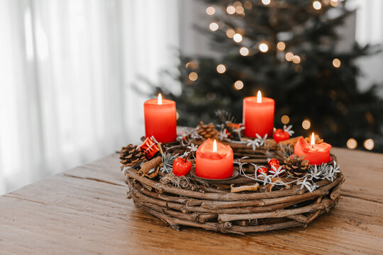 Advent wreath made of branches with four candles burning on Christmas Eve. Hygge time at home with family and friends.