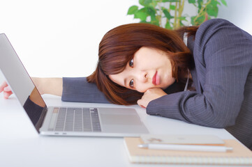 職場のデスクで辛そうな表情をしている女性