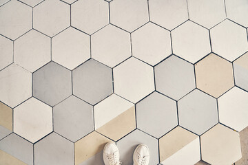 Light-colored sneakers stand on the tile. Finishing the floor with a copy space. The floor is made...