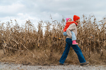 Mother and daughter walking playing together in corn field.