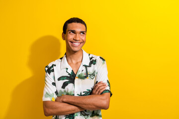 Photo of good mood pleasant man dressed palm print shirt arms folded look at promo empty space isolated on yellow color background