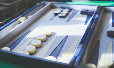 Playing Backgammon. Close view of the board and pieces of two colors. Table games concept.