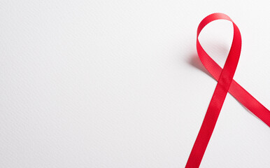 Closeup red ribbon HIV, world AIDS day awareness ribbon on white background. Healthcare and medicine concept.