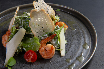 Salad with tomato and shrimp on a dark background.