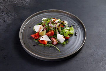 Salad with tomato and cheese on a dark background.