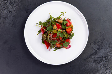 Salad with arugula, tomato and eggplant on a dark background.