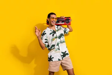 Poster Photo portrait of attractive young man hold boombox dancing have fun wear trendy palms print clothes isolated on yellow color background © deagreez