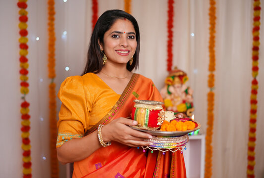 Beautiful Indian woman dressed traditionally in a saree - posing for the camera  Karwachawth celebration. Traditionally dressed woman looking towards the camera while holding a thaali