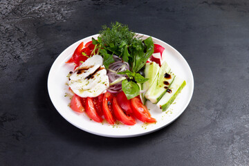 Fresh vegetables, herbs and cheese in a plate. On a dark background.