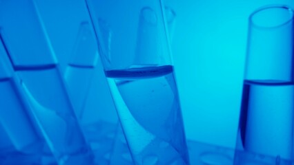 Close up video neon blue light test tubes filled with fluid in a laboratory. Scientific experiment, research, study. Detail shot of lab glassware.