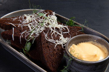 Fried rye croutons and sauce in a plate. On a dark background.