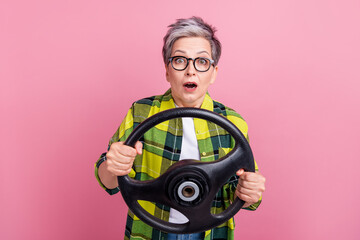 Photo of astonished woman with short hair wear checkered shirt hold steering wheel staring at accident isolated on pink color background