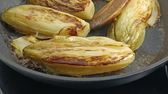 endives brais&eacute;es dans une po&ecirc;le, en gros plan