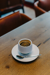 Cup of black coffee on a wooden table in a cafe.