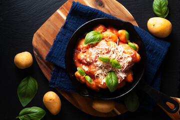 Food concept spot focus homemade gnocchi rosso sauce in skillet iron pan on black background with copy space