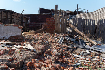 An old ruined wooden house. Broken walls, a ruined roof. Piles of garbage. Natural disasters, war, earthquake