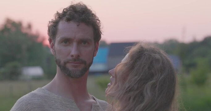 A romantic and sensual moment as a young hetero Caucasian millennial couple passionately embraces, kisses, and enjoys the warm embrace of a sunset backdrop, capturing the essence of love and