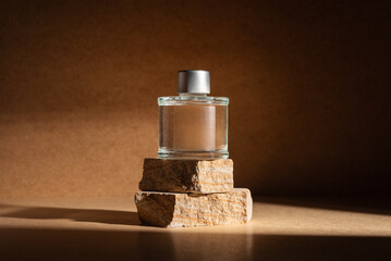 Glass perfume bottle or home fragrance on natural stone podium