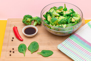 Fresh Green Salad of Avocado, Broccoli, Spinach and Cucumber with Soy Sauce and Red Hot Pepper on Wooden Cutting Board. Vegan Salad. Vegetarian Culture. Raw Food. Healthy Eating and Vegetable Diet