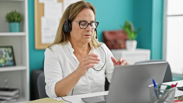 Middle age hispanic woman business worker stressed taking headphones off at the office