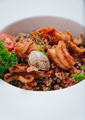 buckwheat with seafood, oyster, tomato and herbs in a deep plate side view