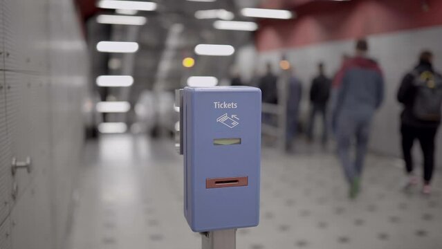 Ticket validator for public transport in blue color on background walking passengers in subway in Munich, Germany. Public transportation ticket stamp machine in metro station in Munchen, Deuschland. 