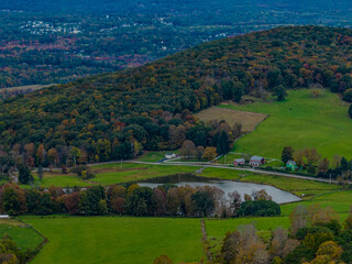 Aerial view of the countryside in Stormville, NY on a cloudy day during the colorful autumn season with a lake in view.