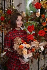 Woman, girl with red rose flowers. Coxy interior with flowers, elegance lady indoor. Fashion beautiful woman in red dress. Autumn decor, summer decoration, floral ornament. Girl with roses bouquet