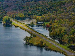 Fototapeta na wymiar Aerial view of the countryside in Stormville, NY on a cloudy day during the colorful autumn season with a lake in view.