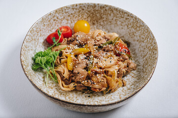 udon noodles with duck meat, herbs, sesame seeds and cherry tomatoes side view