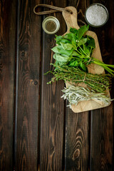 Cooking background with fresh green herbs on wooden board, top view