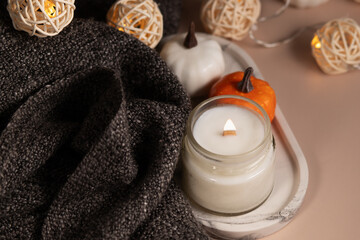 Obraz na płótnie Canvas burning candle and cozy blanket, autumn decorations with pumpkins, Perfumed home interior, Relaxing spa vibes