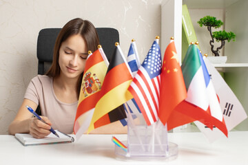 learning languages, immigration, working abroad, paperwork, student at a desk with flags of different countries - obrazy, fototapety, plakaty