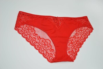 Lingerie. Bright red panties with lace on a white background. Sexy colored women's fashion underwear. - obrazy, fototapety, plakaty
